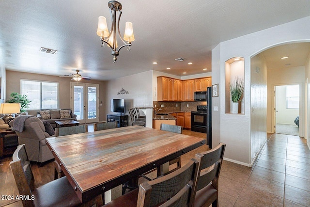 tiled dining space featuring a textured ceiling, sink, and ceiling fan with notable chandelier