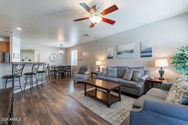 living room with ceiling fan with notable chandelier and dark wood-type flooring