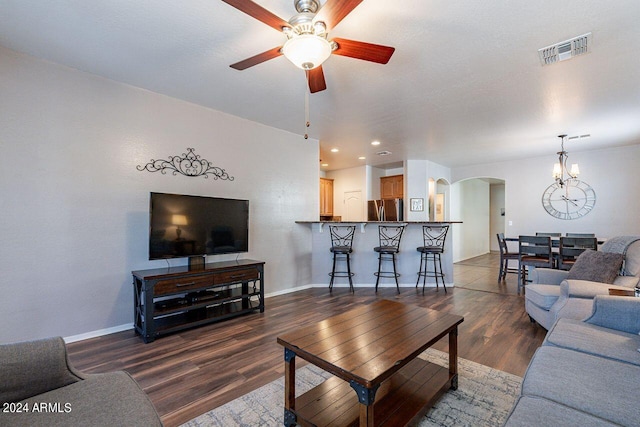 living room featuring dark wood-type flooring and ceiling fan with notable chandelier