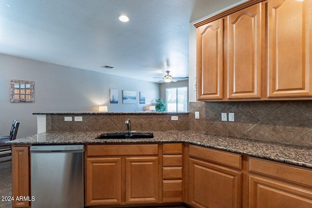 kitchen with dishwasher, kitchen peninsula, sink, ceiling fan, and dark stone counters