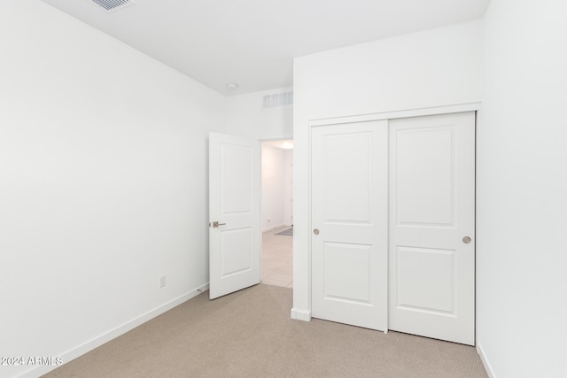 unfurnished bedroom with a closet and light colored carpet