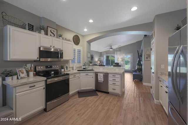 kitchen with kitchen peninsula, stainless steel appliances, ceiling fan, white cabinets, and lofted ceiling