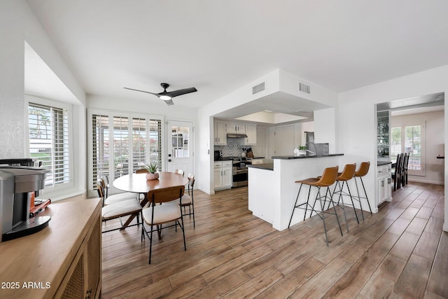 kitchen featuring a peninsula, visible vents, light wood-style flooring, double oven range, and dark countertops