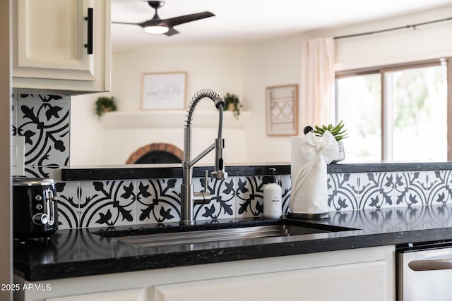 interior details featuring stainless steel dishwasher, dark countertops, tasteful backsplash, and a sink