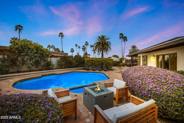 pool at dusk featuring a fenced backyard, an outdoor living space with a fire pit, a patio, and an outdoor pool