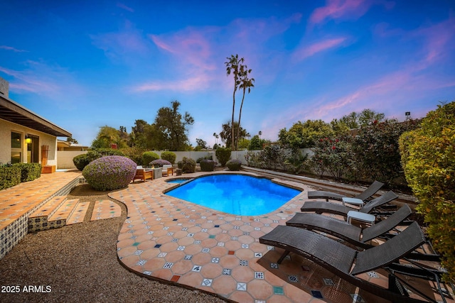 pool at dusk with a fenced backyard, a patio area, and a fenced in pool