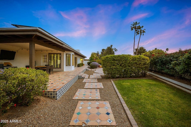 yard at dusk featuring a patio