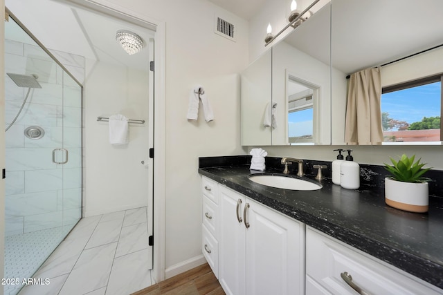bathroom with a stall shower, baseboards, vanity, and visible vents