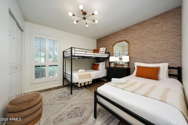 bedroom featuring an inviting chandelier, wood finished floors, a closet, baseboards, and arched walkways