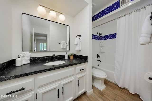 bathroom featuring toilet, wood finished floors, vanity, shower / tub combo with curtain, and visible vents