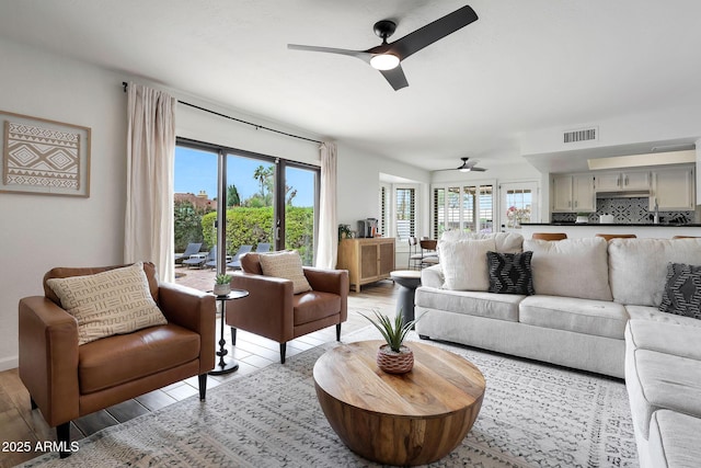 living area featuring light wood finished floors, a wealth of natural light, visible vents, and a ceiling fan