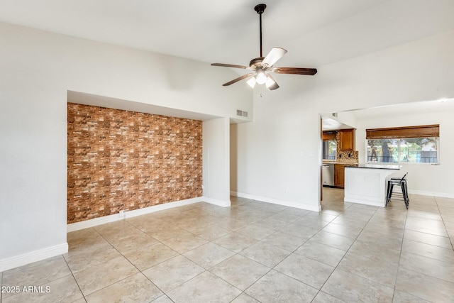 empty room featuring brick wall, high vaulted ceiling, ceiling fan, and light tile patterned flooring