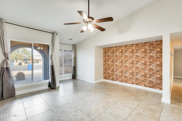 unfurnished room featuring light tile patterned flooring, ceiling fan, brick wall, and vaulted ceiling