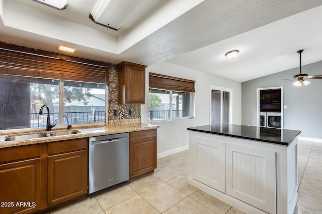 kitchen with sink, light tile patterned floors, dishwasher, backsplash, and washing machine and dryer