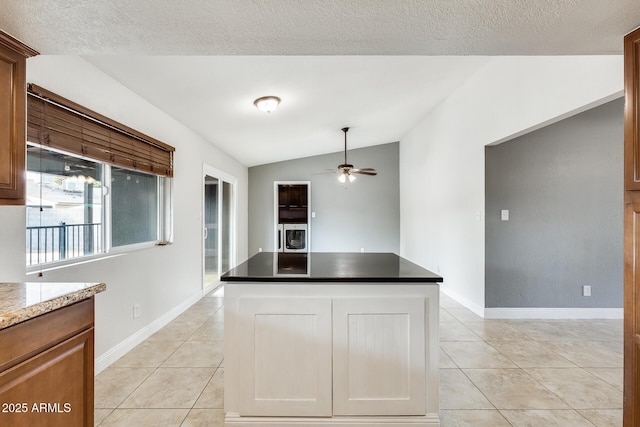 kitchen with light tile patterned flooring, lofted ceiling, a kitchen island, and a textured ceiling