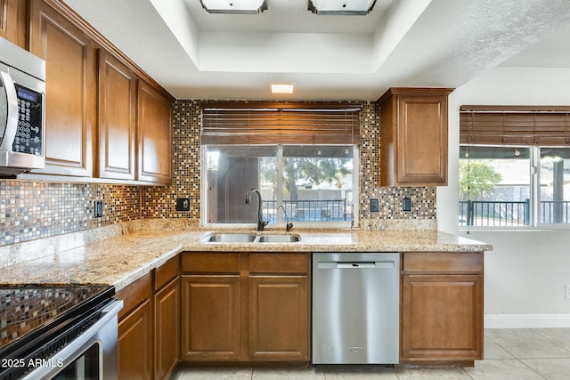 kitchen featuring appliances with stainless steel finishes, a tray ceiling, sink, and plenty of natural light