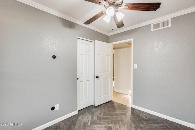 unfurnished bedroom with crown molding, parquet flooring, a closet, and ceiling fan