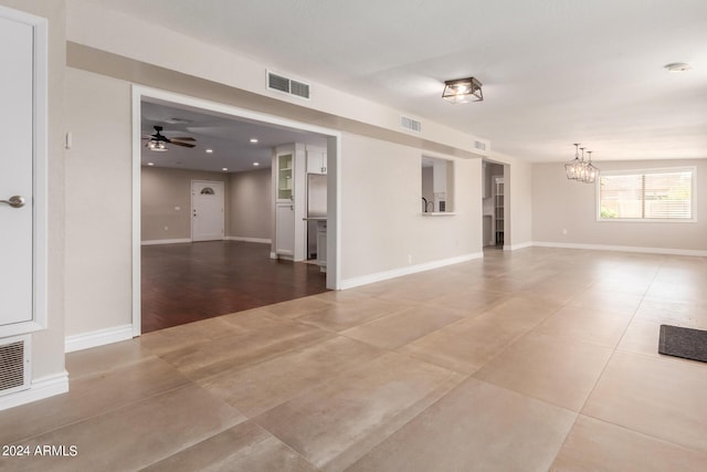 spare room featuring ceiling fan with notable chandelier and tile patterned floors