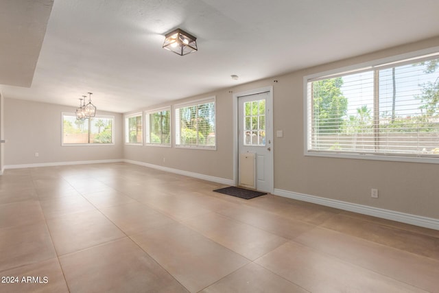 foyer with a notable chandelier, light tile patterned floors, and a wealth of natural light