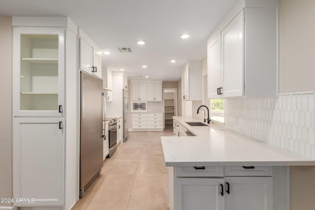 kitchen featuring light stone countertops, appliances with stainless steel finishes, white cabinetry, and sink