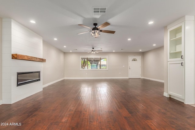 unfurnished living room featuring dark hardwood / wood-style flooring, ceiling fan, and a large fireplace