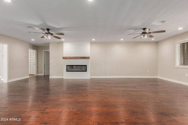 unfurnished living room with dark hardwood / wood-style flooring, ceiling fan, and a fireplace