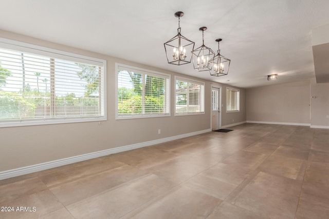 spare room with tile patterned flooring and a chandelier