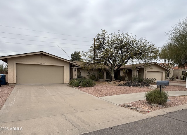 ranch-style house with an attached garage, concrete driveway, and stucco siding