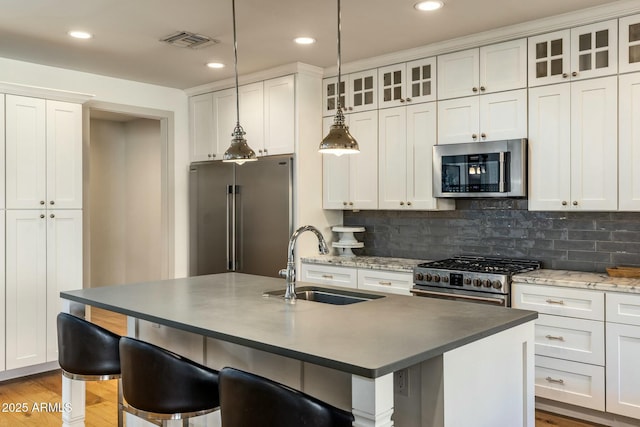 kitchen featuring high quality appliances, white cabinetry, and sink