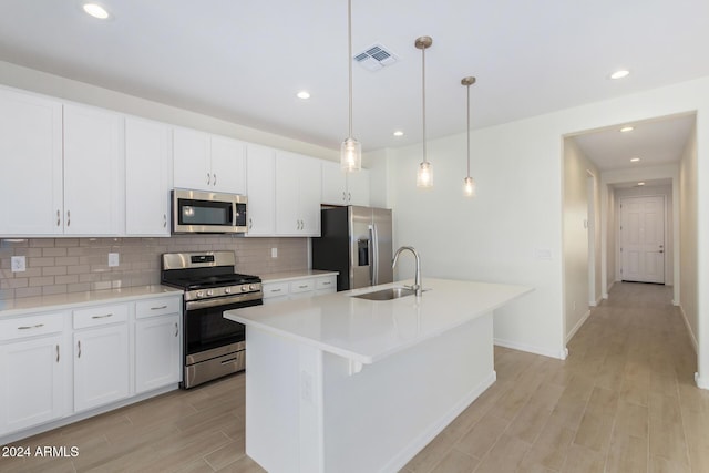 kitchen featuring a kitchen island with sink, sink, hanging light fixtures, white cabinetry, and stainless steel appliances