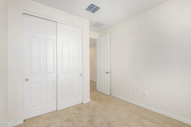 unfurnished bedroom featuring a closet and light colored carpet