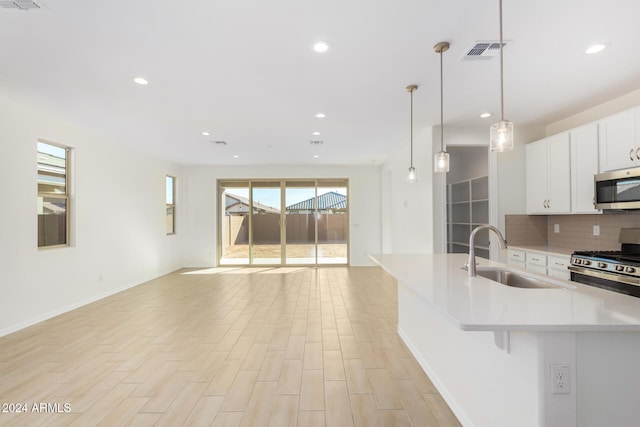 kitchen featuring decorative backsplash, stainless steel appliances, sink, decorative light fixtures, and white cabinetry