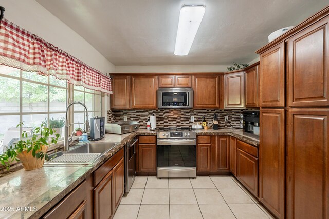10601 N 36th St, Phoenix, AZ 85028 - kitchen with stainless steel appliances, a sink, light tile patterned flooring, tasteful backsplash, and brown cabinets