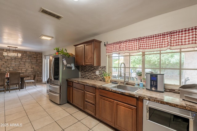 10601 N 36th St, Phoenix, AZ 85028 - kitchen with a sink, freestanding refrigerator, light tile patterned flooring, decorative backsplash, and brown cabinets