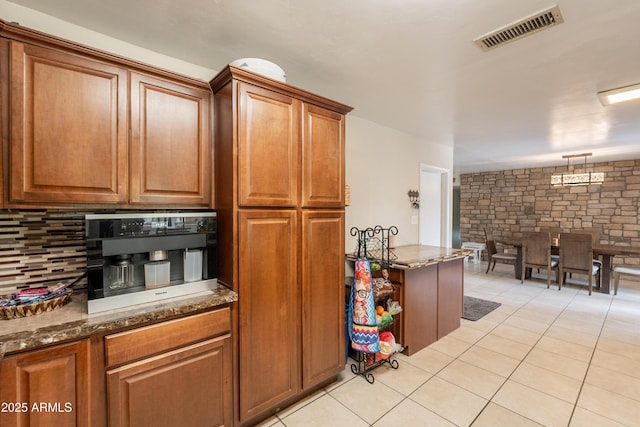 10601 N 36th St, Phoenix, AZ 85028 - kitchen featuring light tile patterned flooring, dark stone countertops, brown cabinets, and decorative backsplash