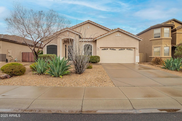 mediterranean / spanish-style home with a tiled roof, stucco siding, an attached garage, and driveway