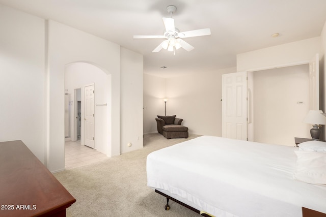 carpeted bedroom with arched walkways and a ceiling fan