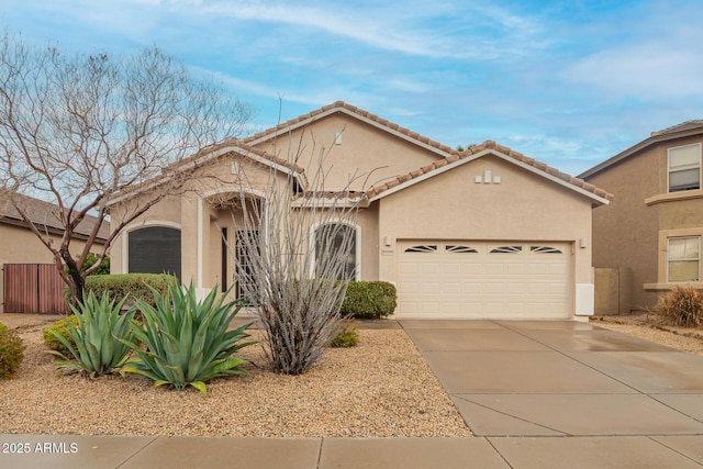 view of front facade with stucco siding, driveway, a tile roof, fence, and a garage