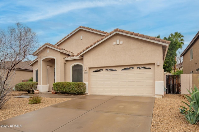 mediterranean / spanish home with fence, a garage, driveway, and stucco siding