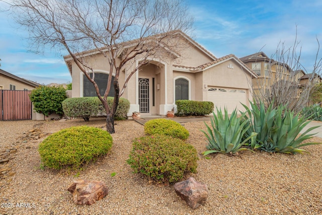 view of front of property featuring a tiled roof, an attached garage, fence, and stucco siding