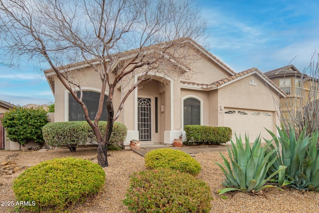 view of front facade featuring stucco siding, an attached garage, and a tile roof