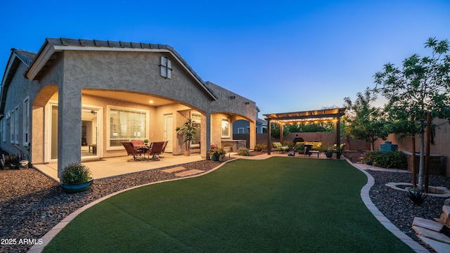 back of property featuring a fenced backyard, a pergola, a yard, a patio, and stucco siding