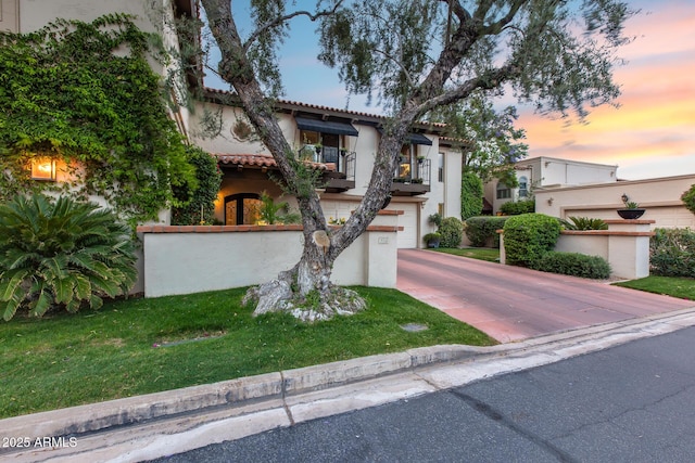 mediterranean / spanish-style home featuring a tile roof, stucco siding, driveway, and a garage
