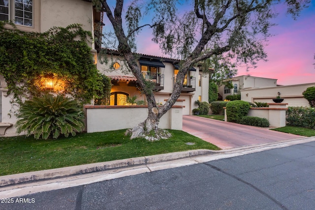 mediterranean / spanish-style home featuring stucco siding, concrete driveway, a tiled roof, a balcony, and a garage