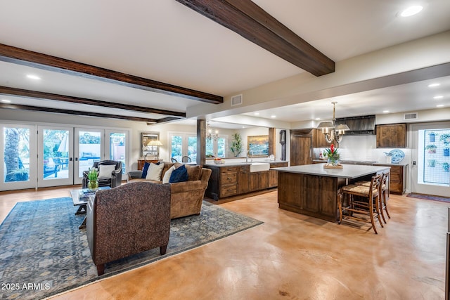 living area with a chandelier, beam ceiling, recessed lighting, and concrete flooring