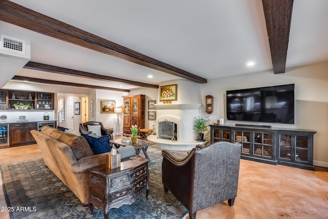 living area with bar with sink, beam ceiling, wine cooler, a fireplace with raised hearth, and recessed lighting