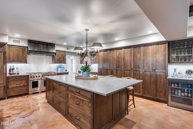 kitchen with double oven range, wine cooler, wall chimney range hood, a kitchen island, and light countertops