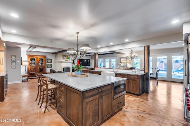 kitchen with a chandelier, a spacious island, stainless steel microwave, and recessed lighting