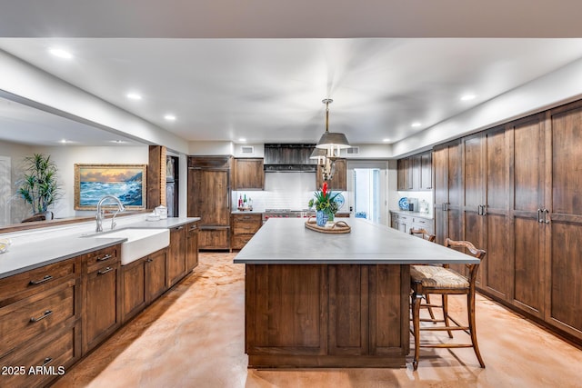 kitchen featuring finished concrete floors, a sink, a kitchen island, light countertops, and recessed lighting