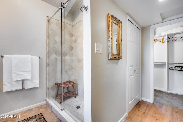 full bath featuring a shower stall, baseboards, a closet, and wood finished floors